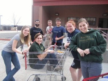 Group photo of students surrounding a student who is in a shopping cart