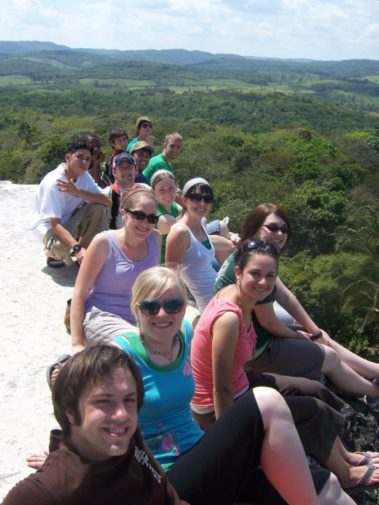 Group of students sitting on a cliff overlooking trees