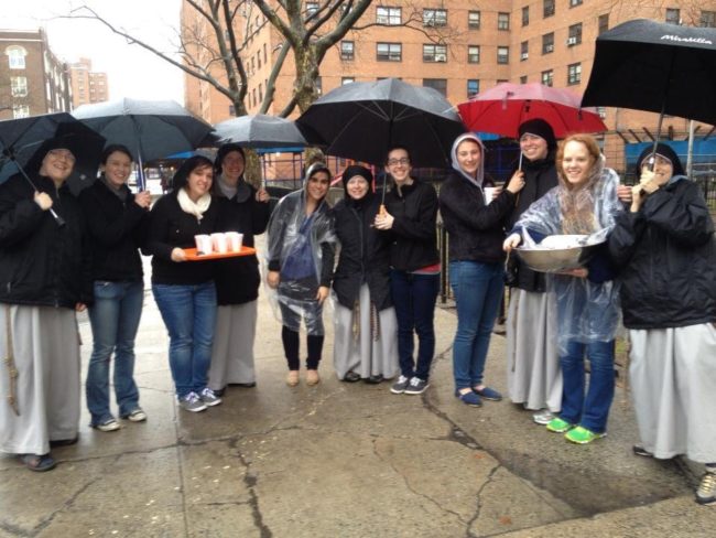 Volunteers standing with umbrellas in the rain Volunteers standing with umbrellas in the rain
