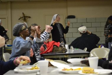 Group of people singing at a soup kitchen