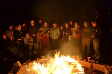 Students standing around a campfire