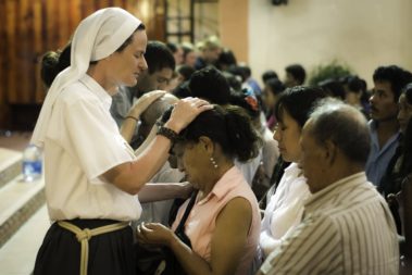 A nun praying over a group of people