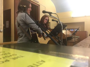 Students playing guitar and singing through microphones