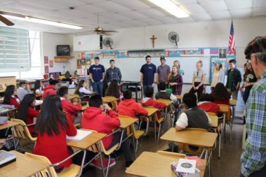 Students talking to children in a classroom