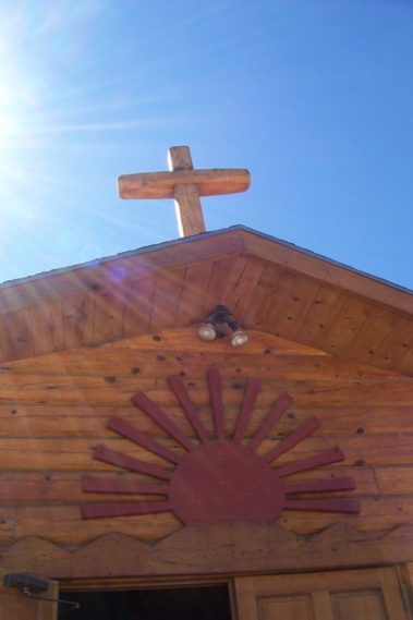 A building with a red sun above its door and a cross on top