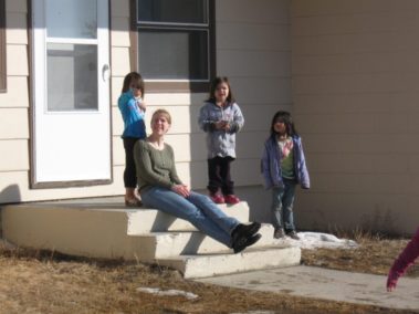 Student and children on the front steps of a house