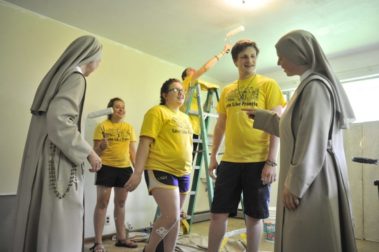 Students and nuns painting a house