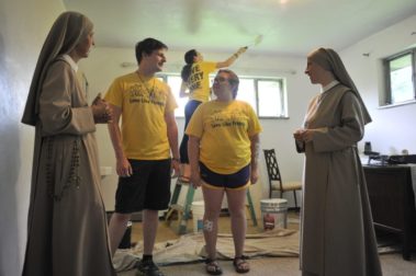 Students and nuns painting a house